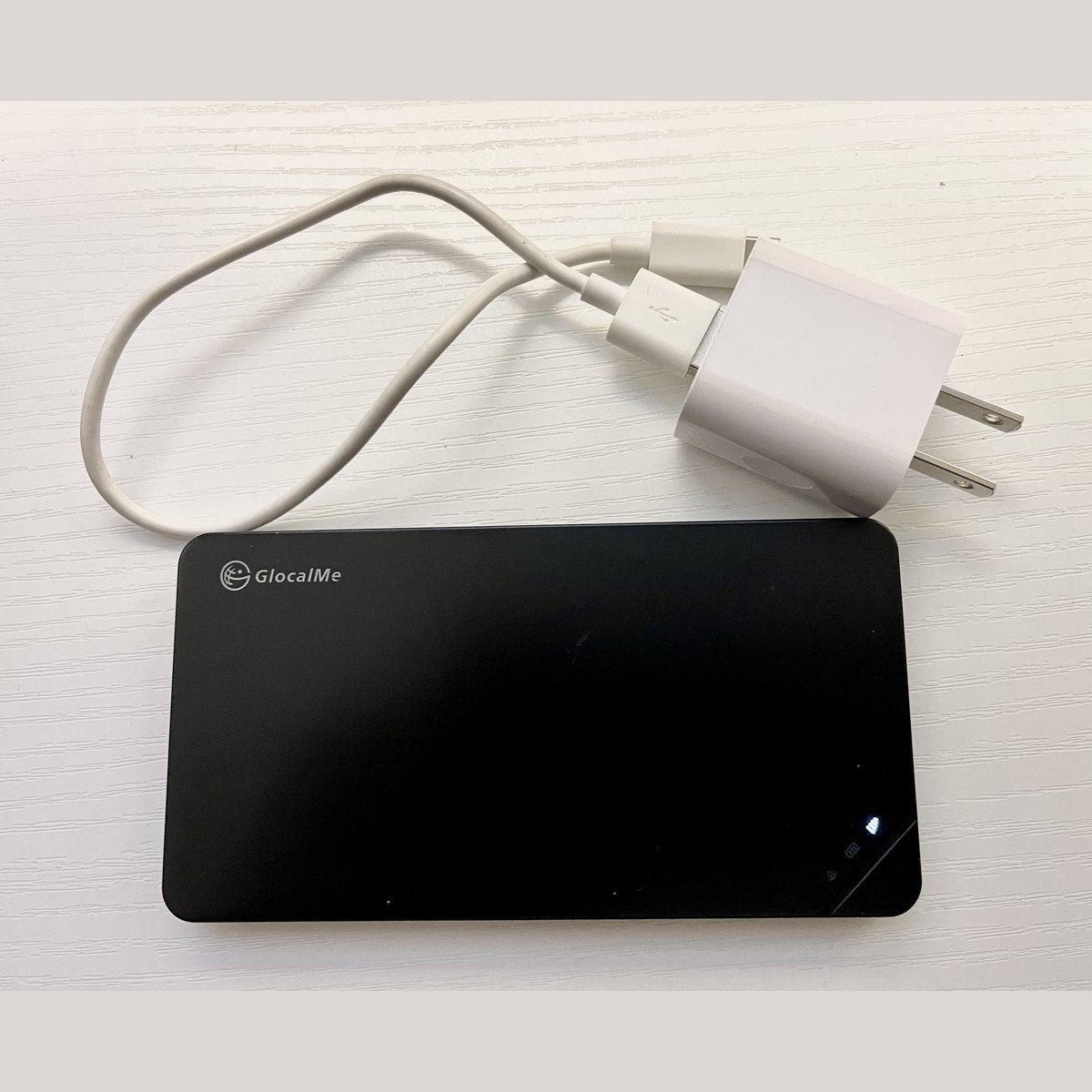 Pocket WiFi router with its charger and cable